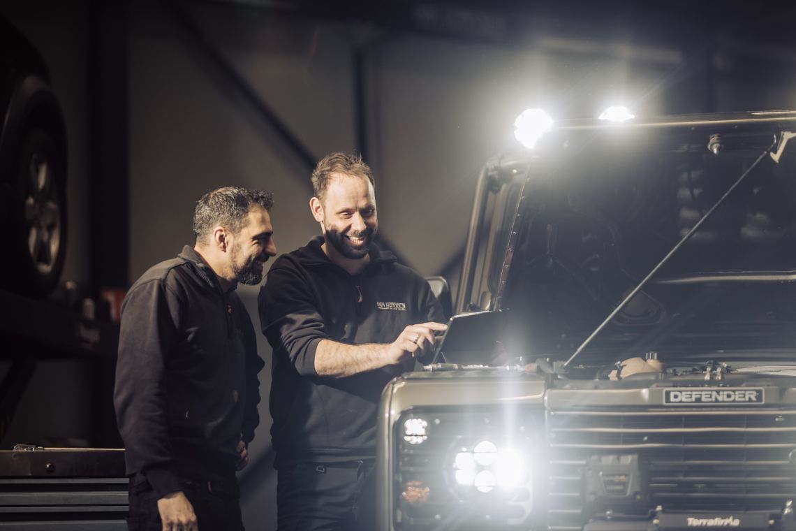 Detailfoto van de koplamp en knipperlicht van een grijze 8 cilinder Landrover Defender