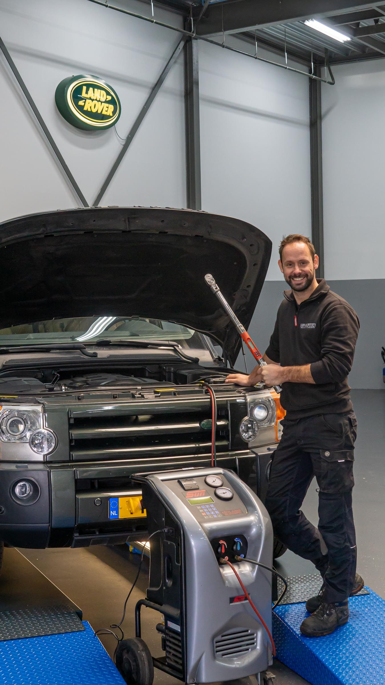 Gerrit van Horssen staat, met een momentsleutel, vóór een Land Rover Discovery 